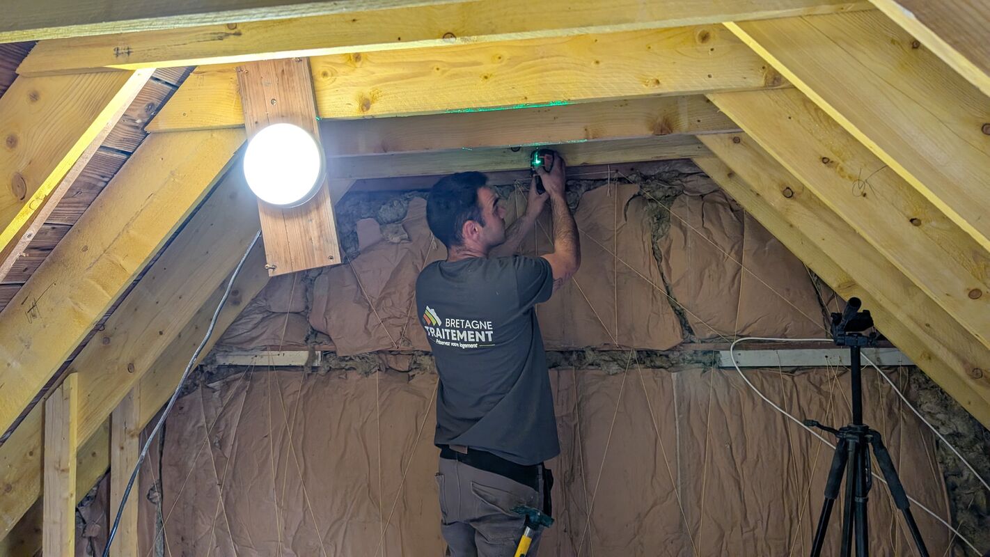 Technicien mesurant l’isolation dans des combles aménagés